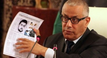 Libyan Prime Minister Ali Zidan holds up copies of foreign newspapers reporting the kidnapping of Abu Anas al-Libi by US special forces